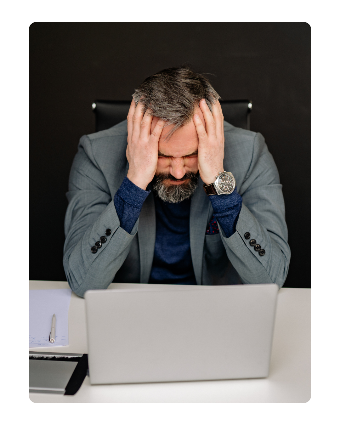 Manager con expresión estresada, manos en la cabeza frente al laptop